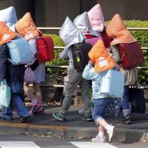 Elementary schoolchildren wear protective headgear as they walk to school in Tokyo, April 25, 2011.   REUTERS/Kim Kyung-Hoon