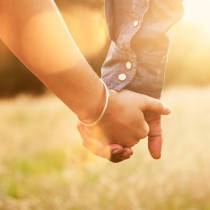 Young couple holding hands with sun-flare.