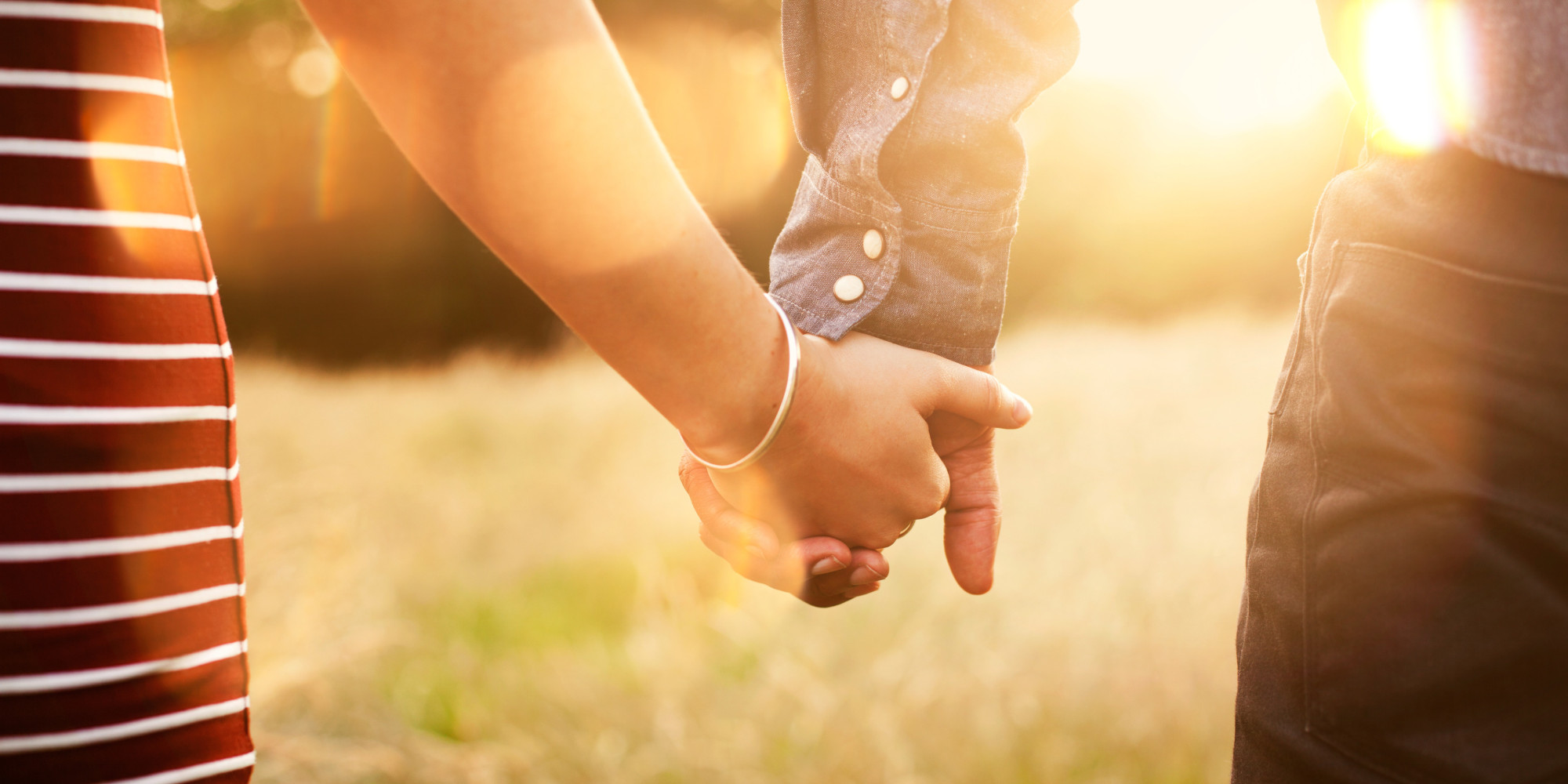 Young couple holding hands with sun-flare.